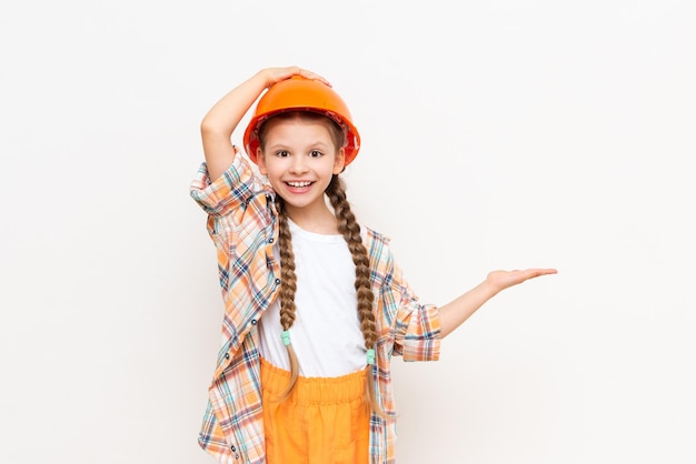 A little girl holds your advertisement in the palm of her hand The concept of repair and construction A teenager in a plaid shirt and a protective helmet on a white isolated background