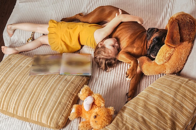 little girl at home on the couch hugging her big red dog