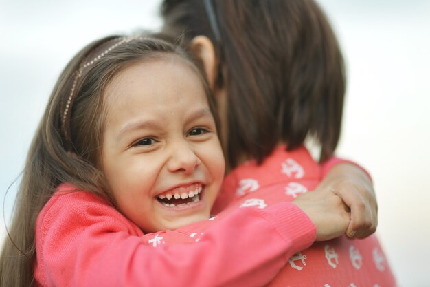 Little girl hugging her mother near the lake