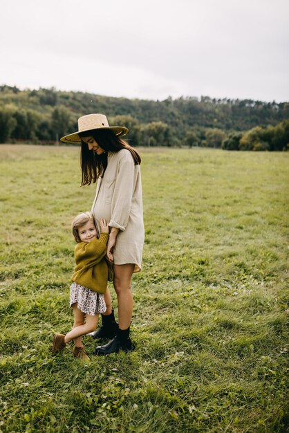 写真 妊娠中の母親の腹を抱きしめている小さな女の子が 妹のコンセプトの内側を聞いています