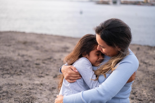 Little girl hugging her tired mother after a long walk by the sea Concept motherhood childhood growth