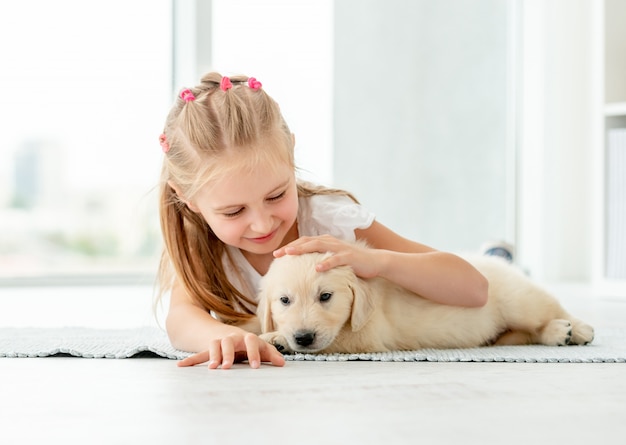 Little girl hugging retriever puppy