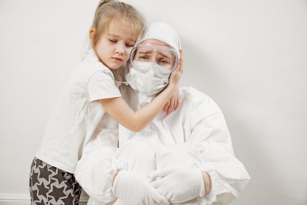 A little girl hugs a doctor in a white protective suit