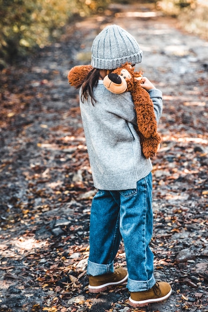 Little girl hugs her bear on a background of nature, autumn, durba.