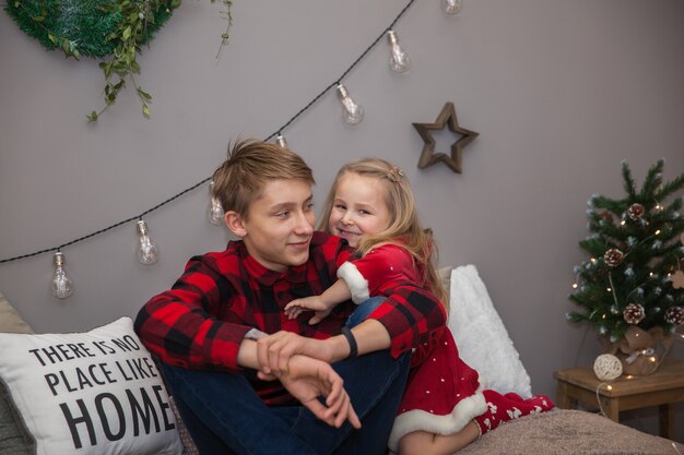 A little girl hugs her brother in Christmas clothes, family look, a New Year's concept