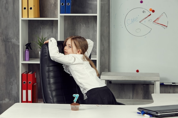 A little girl in the image of an office worker is idling while working