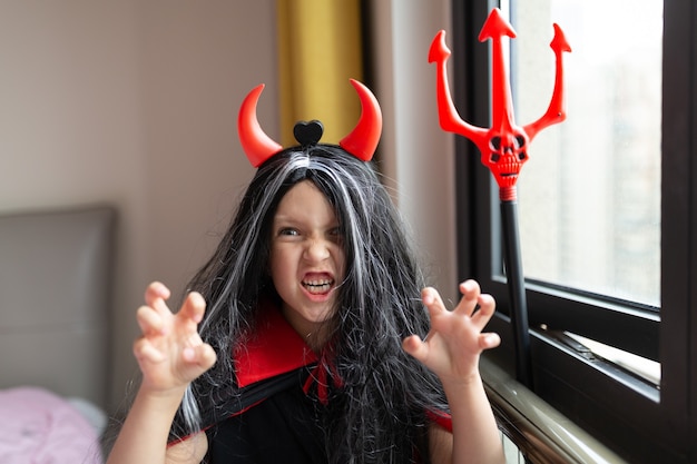 写真 自宅で赤い角を持つ悪魔の衣装を着た少女