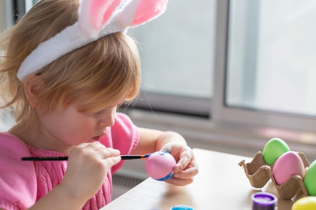 사진 부활절 토끼 귀를 입은 작은 소녀가 다채로운 달을 그리는 부활절 축제와 공예 개념