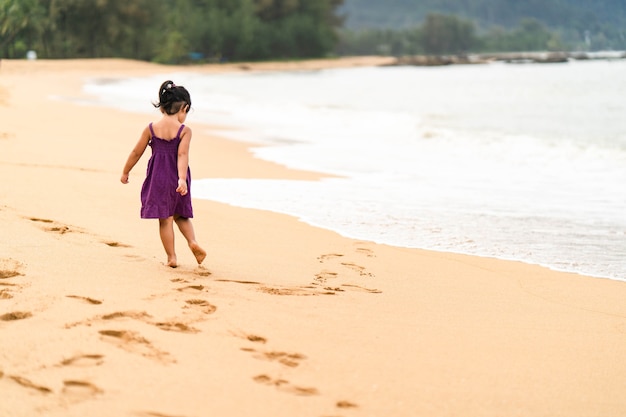 사진 해변에 산책하는 보라색 드레스에 어린 소녀.