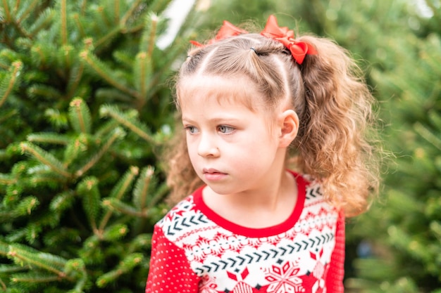 写真 クリスマスツリーファームで赤いドレスを着た少女。