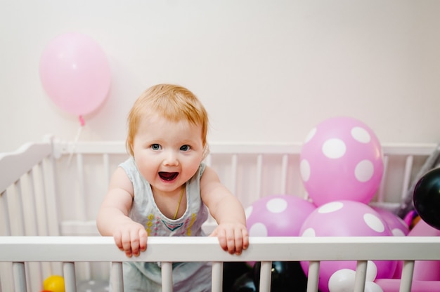 Little girl infant  in bed with colored balloons on her birthday