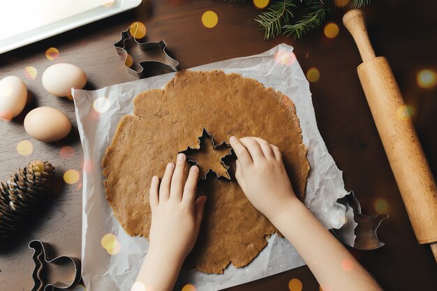 La bambina sta cuocendo i biscotti del pan di zenzero di natale. foto di alta qualità