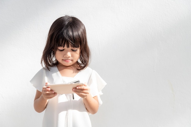 A little girl is concentrated on the phone look at the smartphone technology concept for children