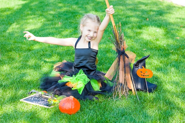 The little girl is dressed in a witch costume, a black hat and black lipstick on her lips. Halloween.