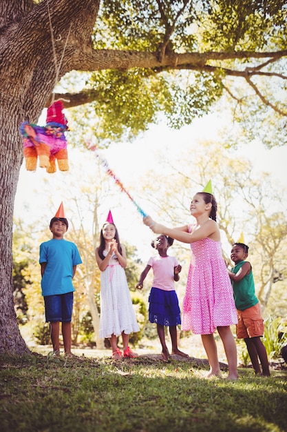 Photo little girl is going to broke the pinata for her birthday