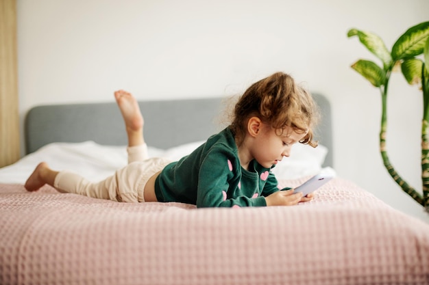 Foto una ragazzina sta guardando felicemente uno smartphone giocando o guardando dei cartoni animati