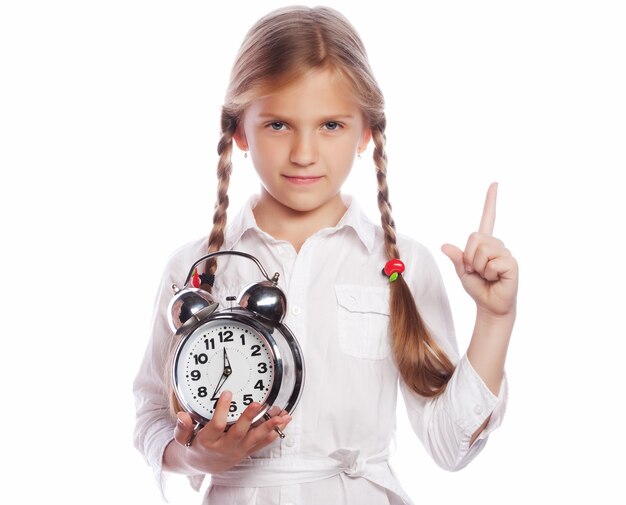 Little girl is holding clock while pointing up with her index finger