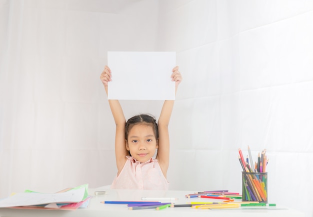 小さな女の子は手にコピースペース、子供の図面の概念と空の紙を保持しています。