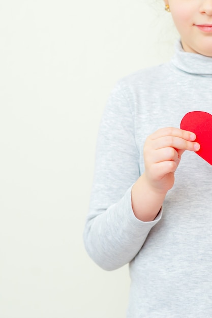 Little girl is holding red little heart