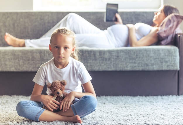 La bambina sta tenendo un orsacchiotto e sta esaminando la macchina fotografica.