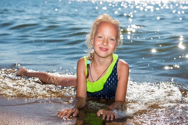 어린 소녀는 화창한 날 바다에서 웃고 수영을 하고 있다