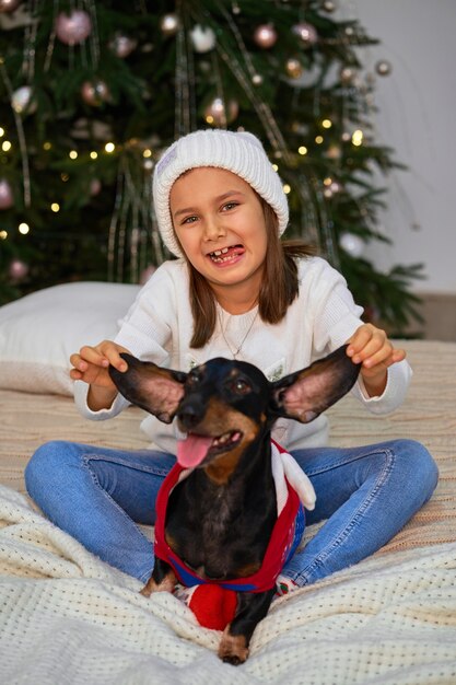 小さな女の子は彼女の友人、ダックスフント犬と一緒に笑っています