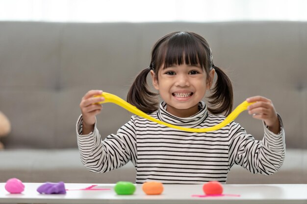 Photo the little girl is learning to use colorful play dough in a well lit room