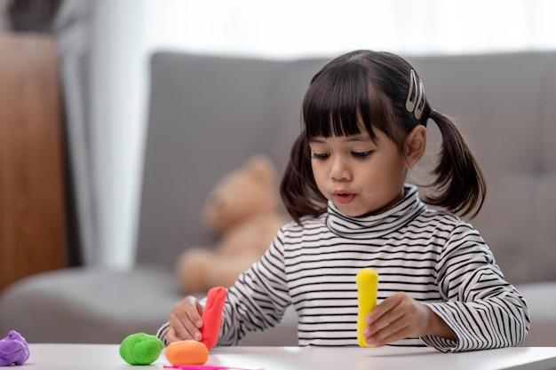 Photo the little girl is learning to use colorful play dough in a well lit room