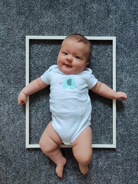 Photo a little girl is lying on the floor in a photo frame and smiling