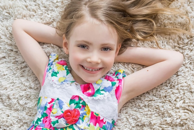 Little girl is lying on the white carpet