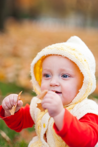 Little girl is playing in the autumn park with a smile.