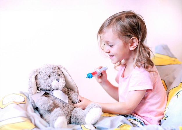 the little girl is playing doctor with a stuffed rabbit