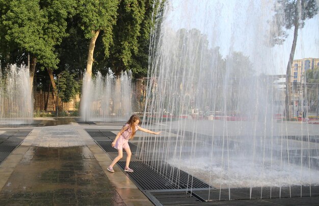 little girl is playing in the fountain