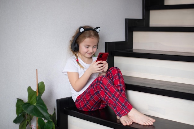 A little girl is playing a game, in an online mobile application, wireless headphones for a child