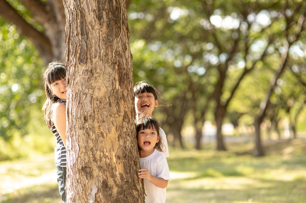 Little girl is playing hide-and-seek hiding face in the park