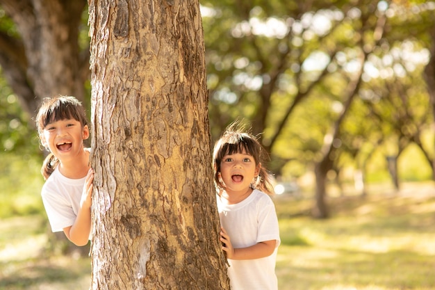 Little girl is playing hide-and-seek hiding face in the park