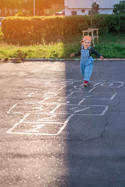 小さな女の子が遊び場で石けり遊びをしている