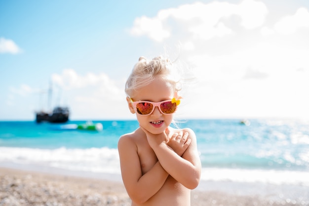 Little girl is playing in the sand by the sea.