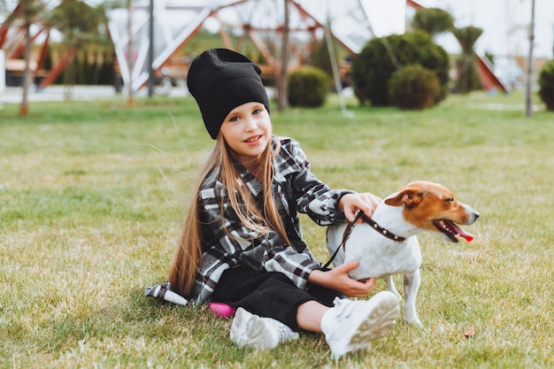 小さな女の子が公園の芝生で犬と遊んでいる ジャック ラッセル テリアの子供が犬におもちゃを与える