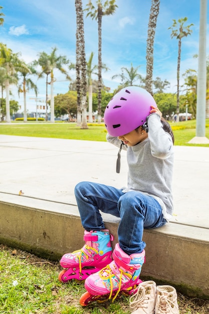 小さな女の子はスケートをするために彼女の保護ヘルメットをかぶっています