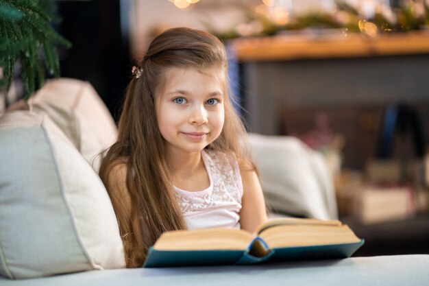 A little girl is reading an interesting book. Education and leisure of children.