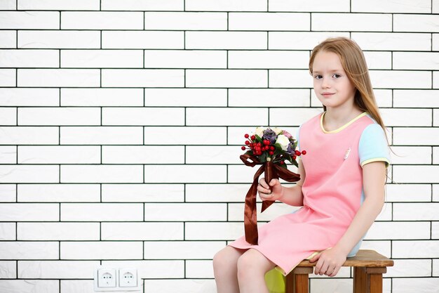 little girl is sitting on a chair and posing on the camera