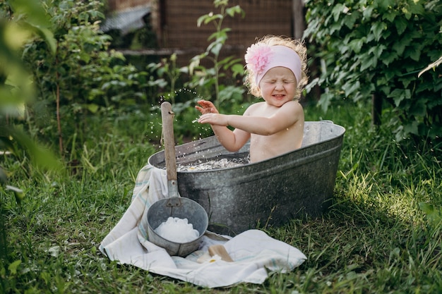 a little girl is sitting in a tin tub with water splashing and rejoicing