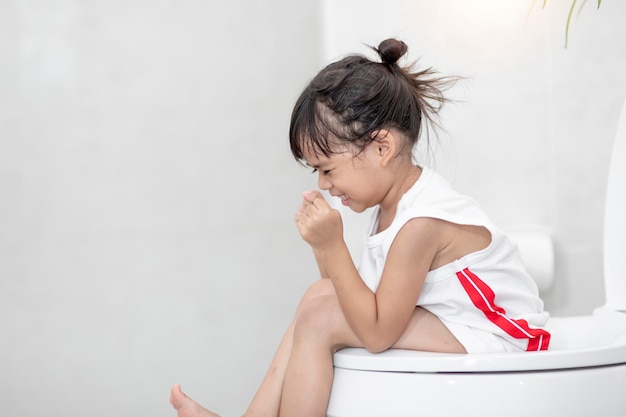 The little girl is sitting on the toilet suffering from constipation or hemorrhoid