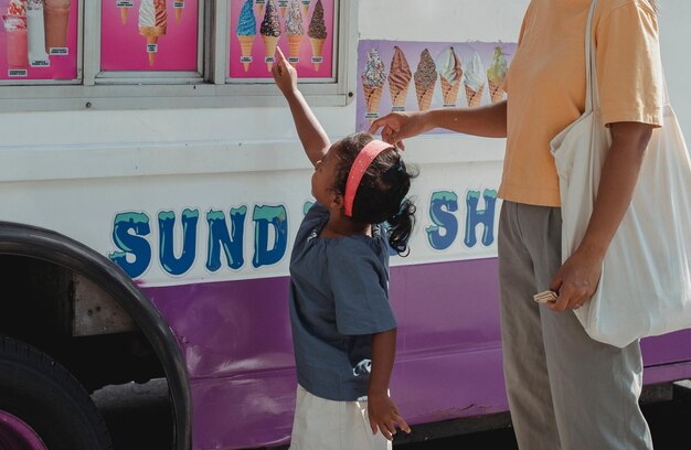 A little girl is standing in front of a ice cream van