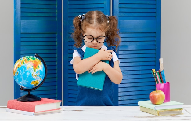 Little girl is studying while wearing a graduation cap