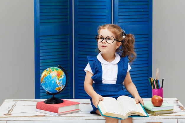 Little girl is studying while wearing a graduation cap