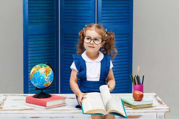 Little girl is studying while wearing a graduation cap