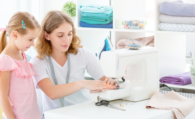 Little girl is taught to sew