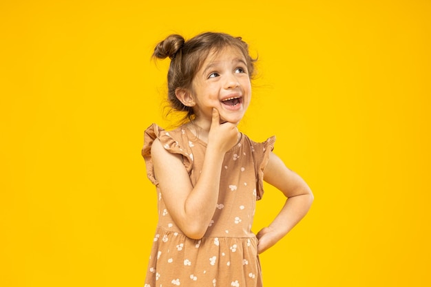 A little girl is thinking on a yellow background